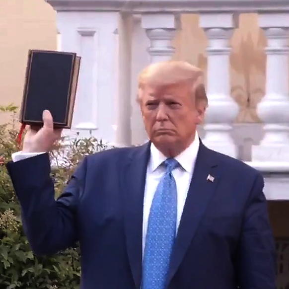 Poor quality photo of Donald Trump holding a Bible while Jan. 6 riots are happening.